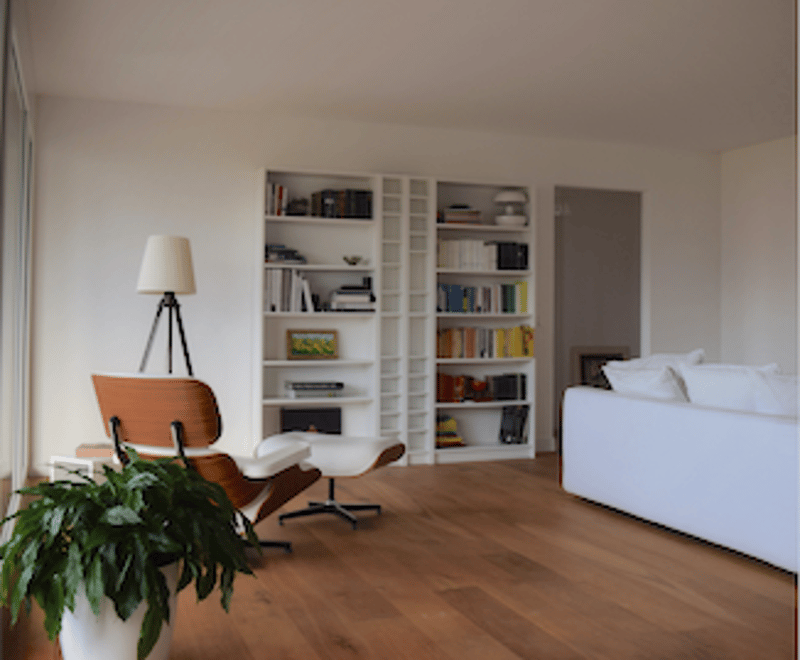 white walls, wooden floor, white sofa, lamp, chair, bookshelf, plant