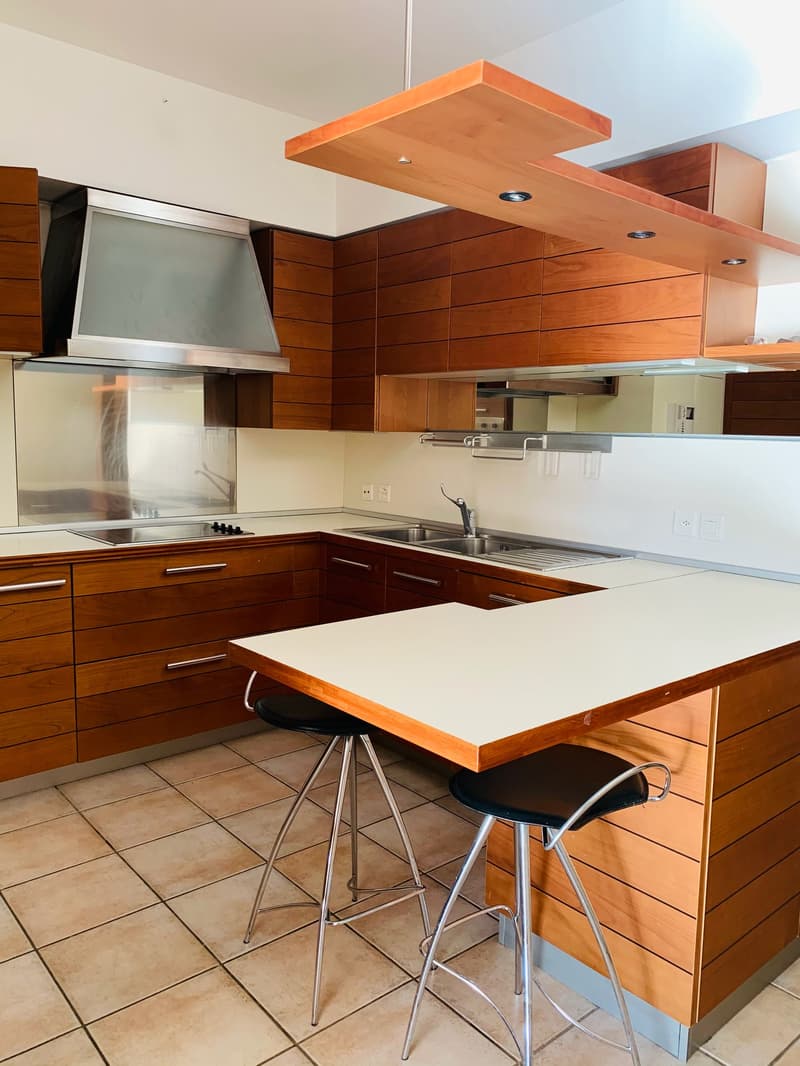 modern kitchen with wooden cabinets, tiled flooring, stainless steel appliances, center island with stools, open shelving, white countertops, power outlets, sinks, and faucets