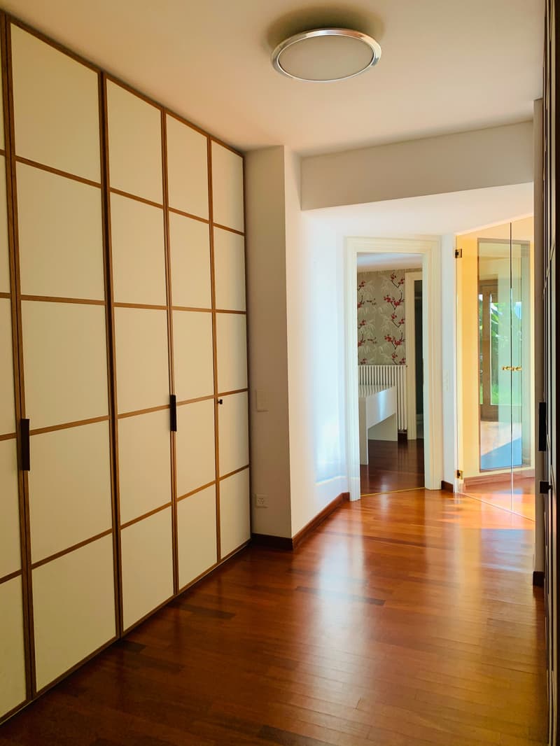 Wooden floors, a large wardrobe, two doors leading to other rooms, a ceiling lamp, a power outlet.