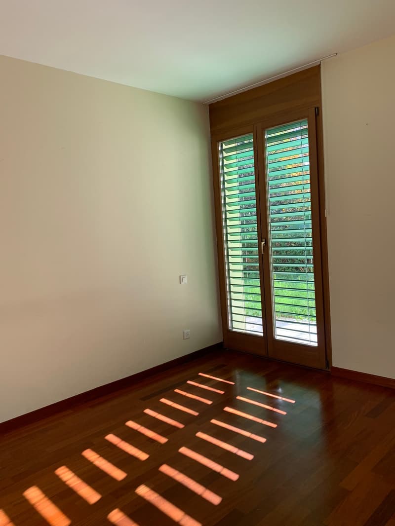 Empty room with wooden floor, sliding doors, no furniture, white walls