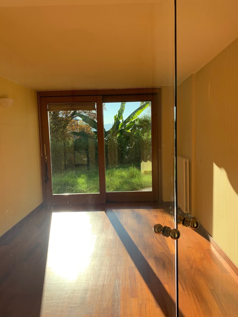 modern sliding glass door leading to a grassy outdoor area, warm wooden floor, glass partition wall, white radiator, yellow painted walls