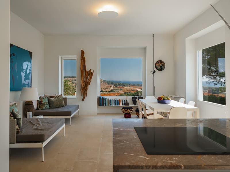 Open-plan living and dining area with large windows, modern furniture, and a view of the countryside