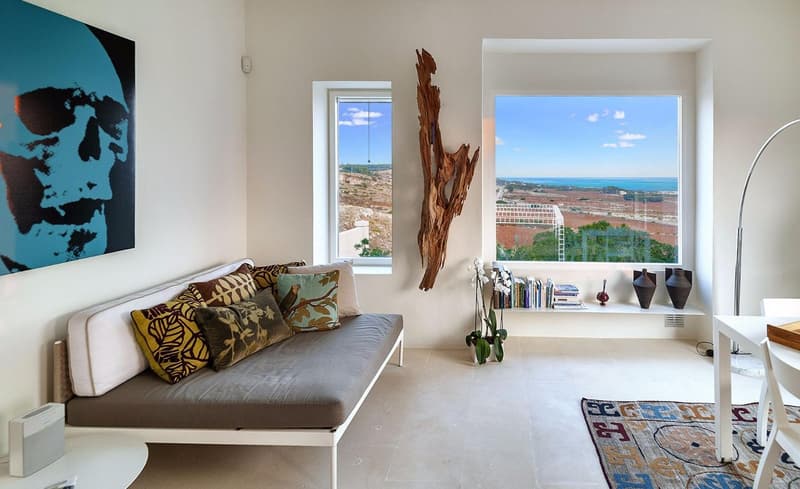 modern living room with a couch, large windows, a rug, a table, and a painting