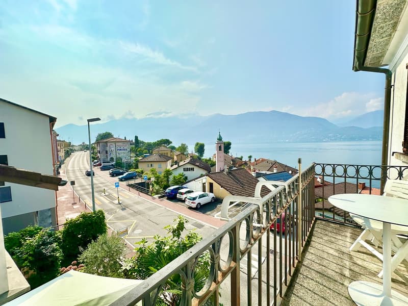 Balcony with railings, table and chairs, view of the street and lake