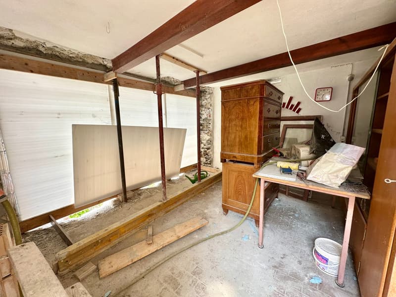 unfinished room, wooden beams, wooden cabinet, desk, bucket, hose, clock, mirror
