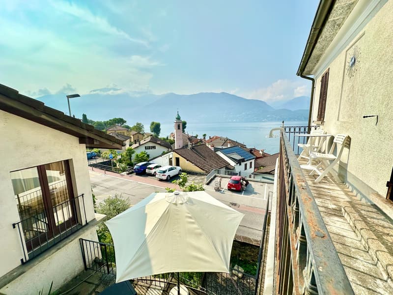 balcony, white umbrella, view of the lake and mountains, cars parked on the street