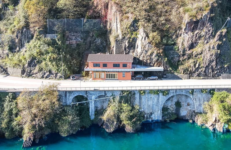 building on a cliffside, above a river, near cars and a bridge