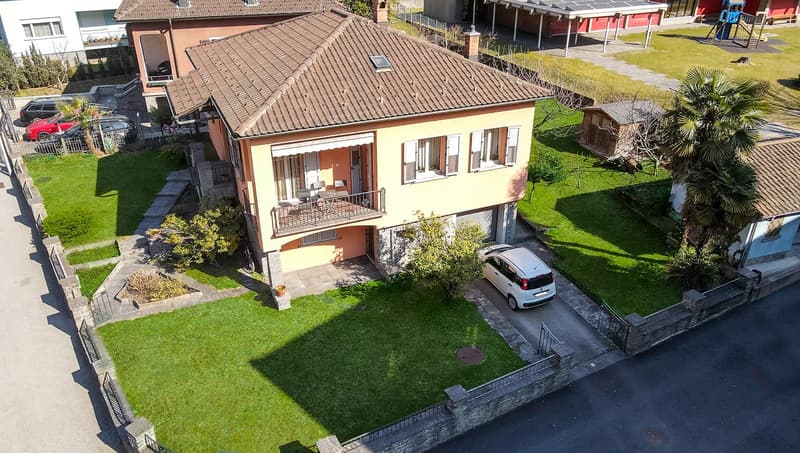 2-story house with red tile roof, yellow exterior walls, balcony, garden, and parking space