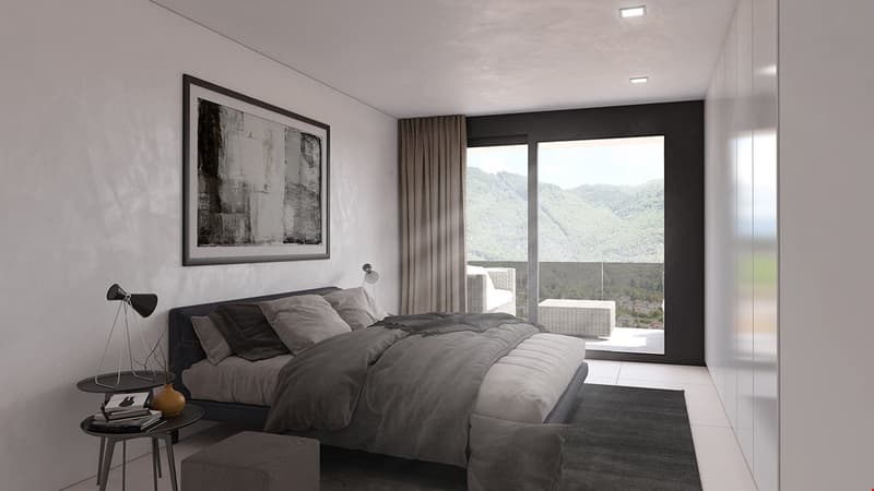 Spacious bedroom with large windows offering a scenic mountain view, dark curtains, gray bedding and decor, framed artwork on the wall, and a side table with a lamp.