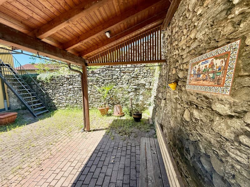 covered patio, wooden ceiling, brick floor, stone wall, potted plants, decorative tile, metal stairs