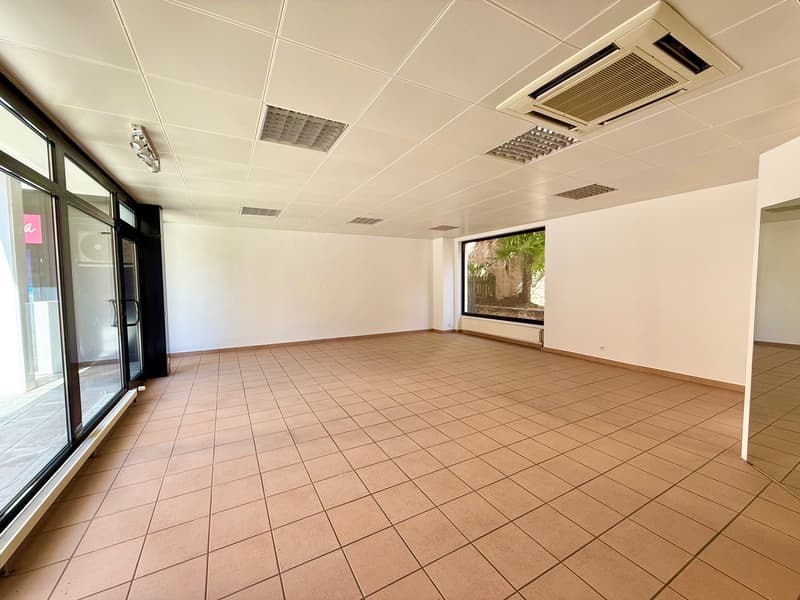 large empty room, white walls, tiled floor, large glass windows, ceiling mounted air conditioning