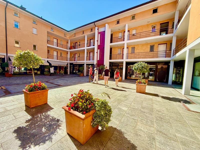 4-story building, multiple balconies, tiled outdoor space, trees, plants, shops