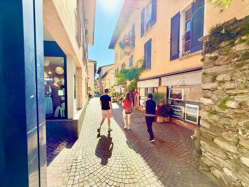 two people walking, three buildings, cobblestone street, blue shutters