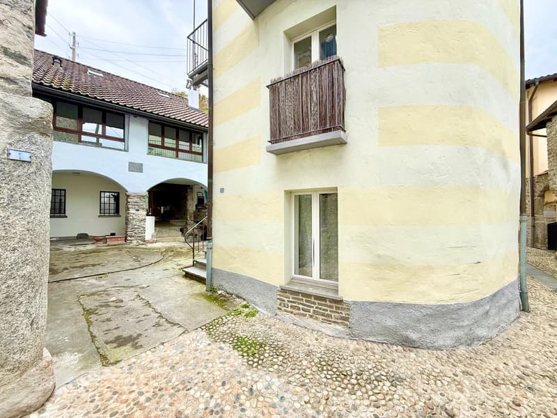 two-story yellow and white building, paved entrance, balcony on second floor, stairs