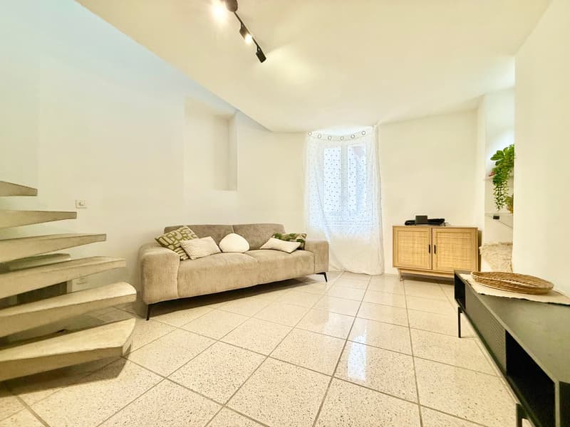 white walls, tiled floor, couch with pillows, wooden cabinet, plants