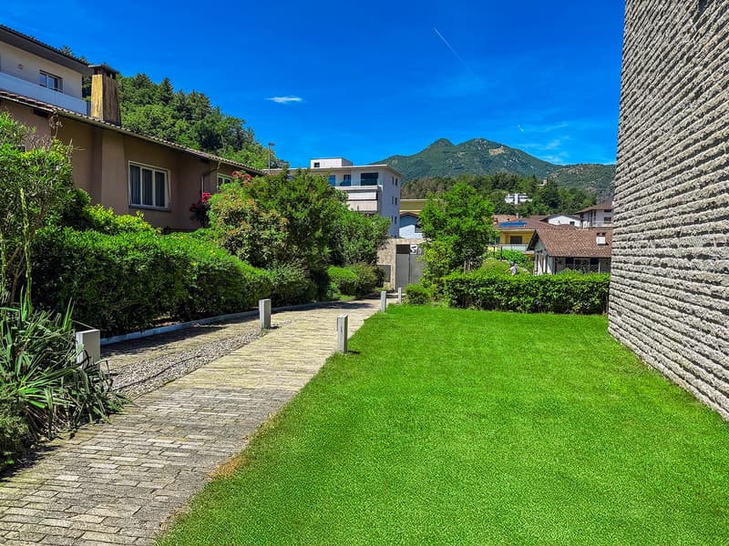 Trees, bushes, stone pathway, green lawn, buildings, mountains