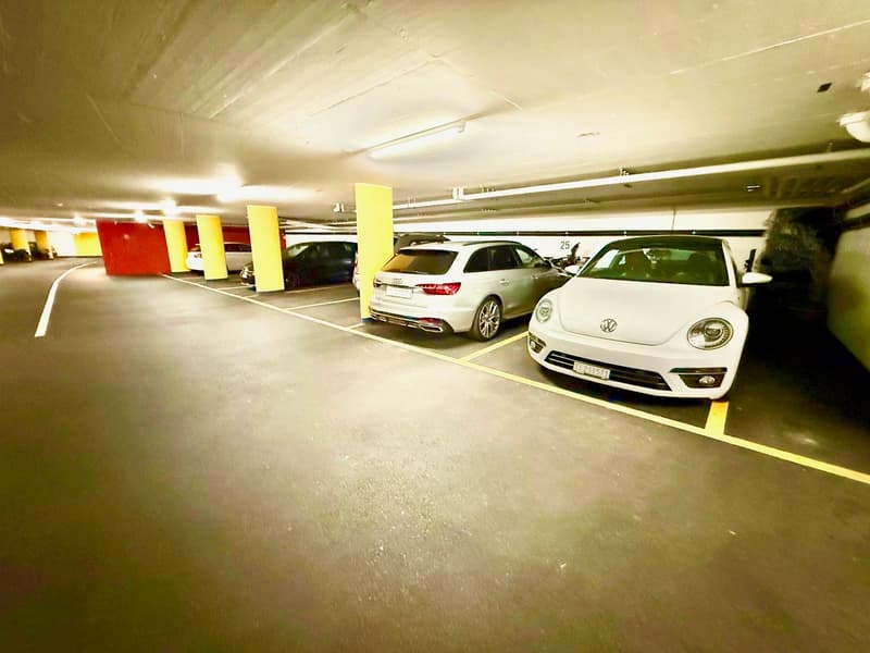 large parking area with multiple cars parked, yellow and red columns