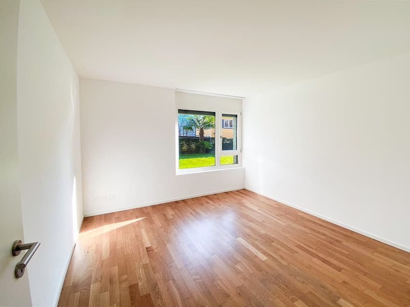 empty room, white walls, wooden floor, window with view of garden