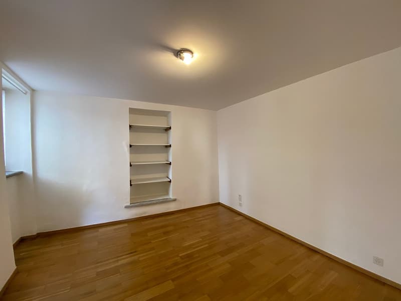 empty room, wooden floor, white walls, built-in shelves, ceiling light, power outlets