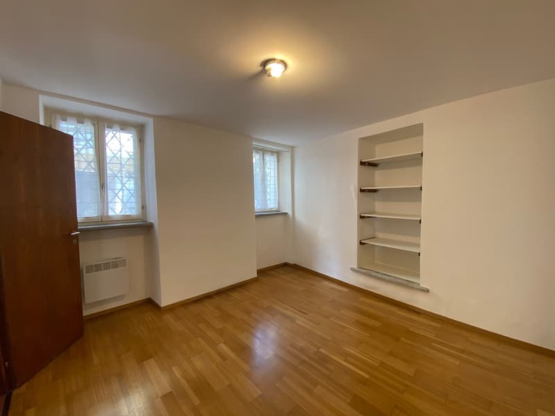 empty room, hardwood floor, built-in shelves, two windows, ceiling light