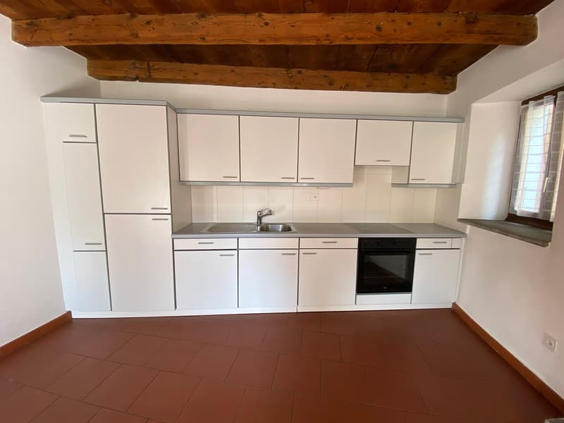 All white cabinets, tiled flooring, silver sink, white countertop, integrated oven and dishwasher, small window.