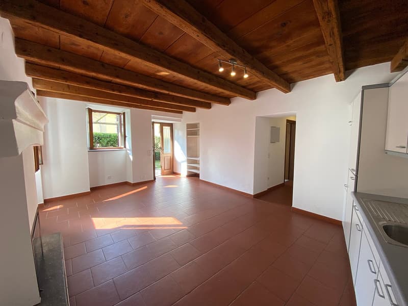 large empty room, wooden ceiling, white walls, brown tiles, fireplace, small window, small room on the left side