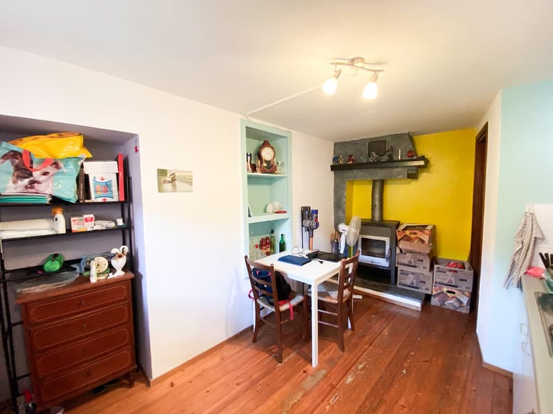 A room with wooden floor and yellow wall. There is a table and chairs and a fireplace.