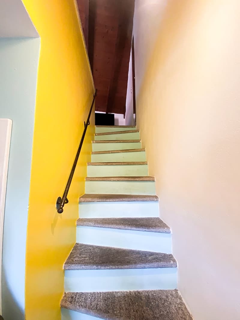 gray carpet, yellow painted wall, metal railing