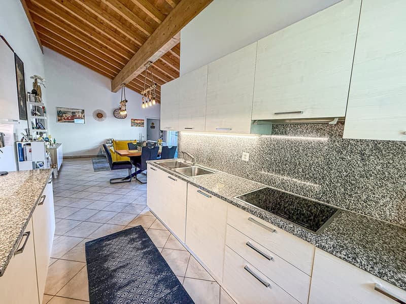 modern kitchen, white cabinets, granite countertops, double sink, stovetop, dishwasher, washing machine, wooden beams, tiled floor, dining area with table and chairs