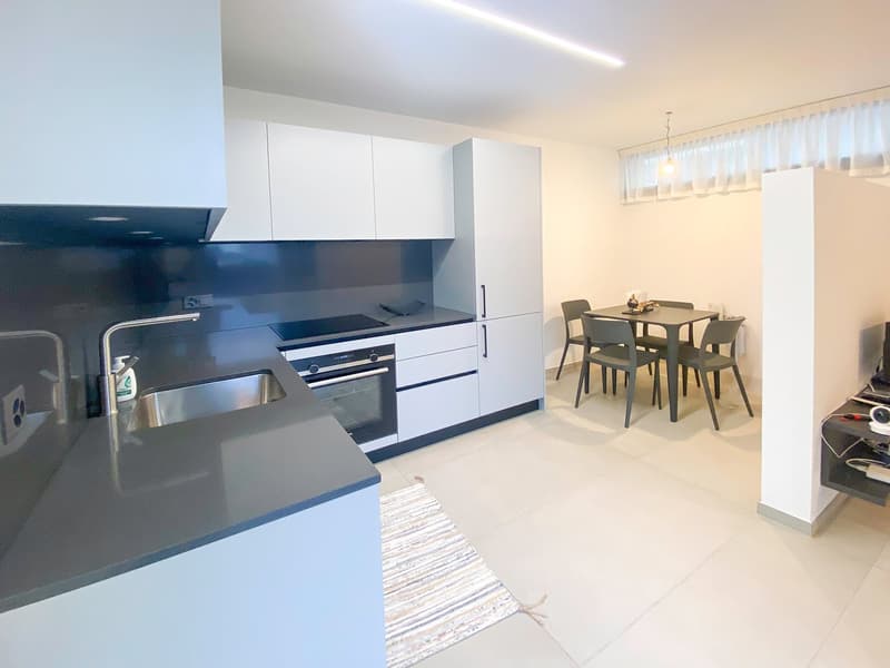 Kitchen with dining area, modern white cabinets, black countertops, gas stove, oven, sink, dining table with chairs, white flooring