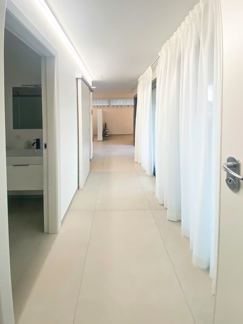 white tile flooring, white walls, open doors, bathroom sink, white shower curtains