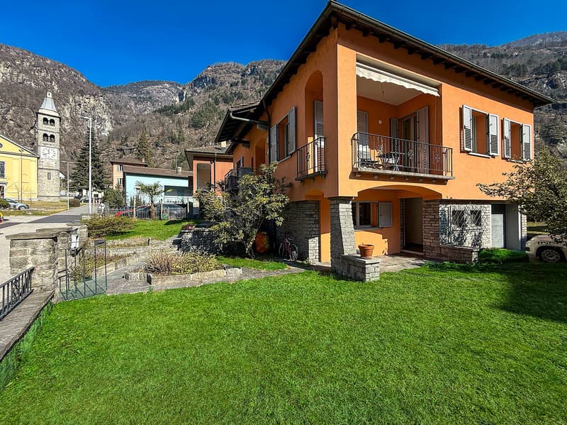 Orange two-story house with balcony, brick foundation, steeple building in the background