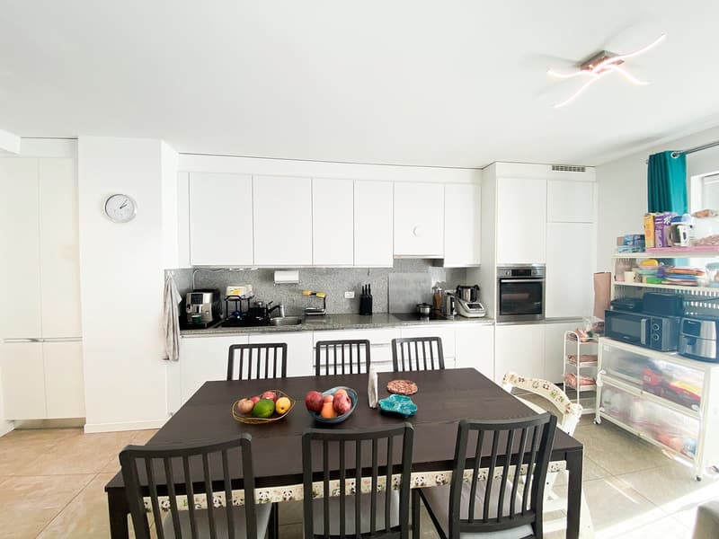 Dining room with white kitchen cabinets, black dining table, microwave, refrigerator, oven, coffee maker, and washing machine.