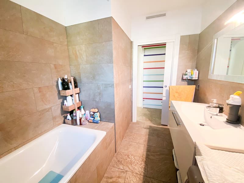 Bathroom with bathtub, sink, mirror, tiled floor and walls