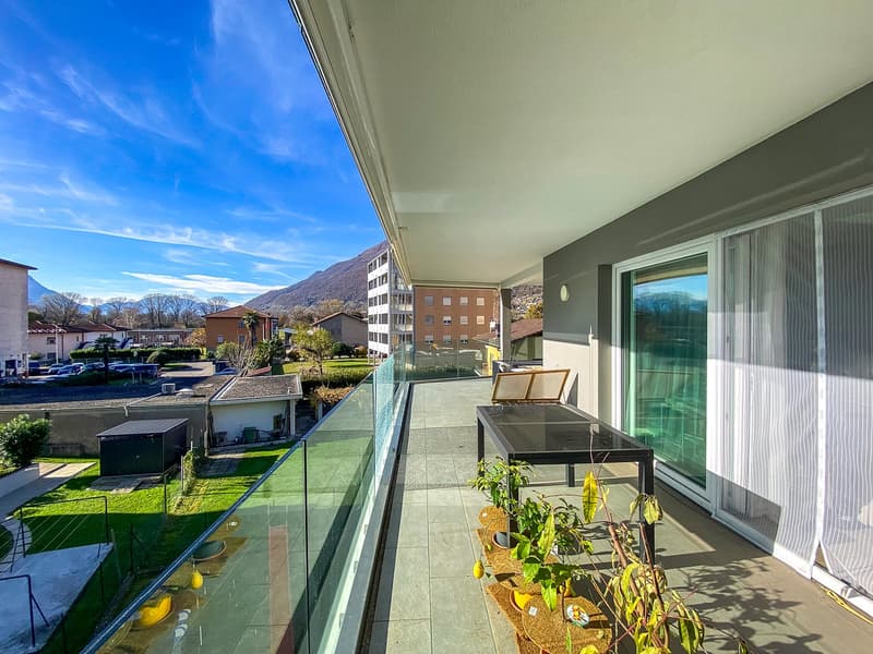 glass railing balcony, table, chairs, plants, view of the town