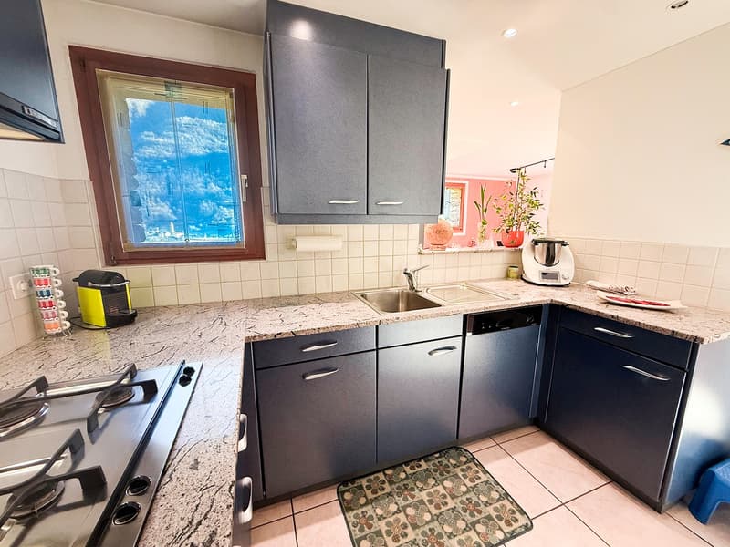 marble countertop, double stainless steel sink, granite backsplash, electric kettle, coffee machine, dishwasher, gas stove, blue cabinetry, overhead cabinets
