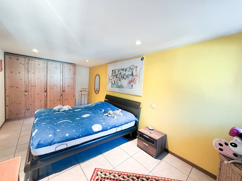 Large wooden wardrobe, double bed, bedside tables, artwork on the wall, rug, mirror, wooden shelves.