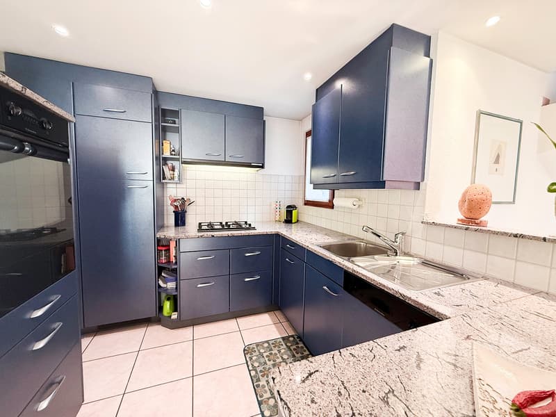 Modern kitchen, with blue cabinetry, granite countertops, a gas stove, a dishwasher, a sink with a faucet, a built-in oven, and a refrigerator.