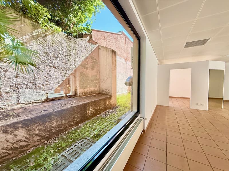Large window with view to outside, wall-mounted radiator, tiled floor, white walls, ceiling lamps