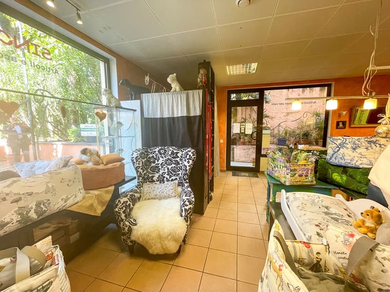 A living room with wooden furniture, carpets, and decorative items. The room has a large window showing the outdoors.