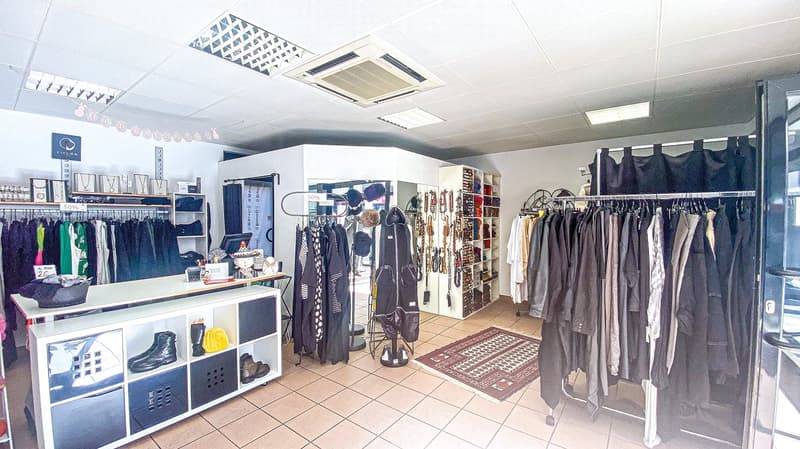 Clothing store, clothing racks, hanging jackets, shoe display, decorative items, carpet, desk