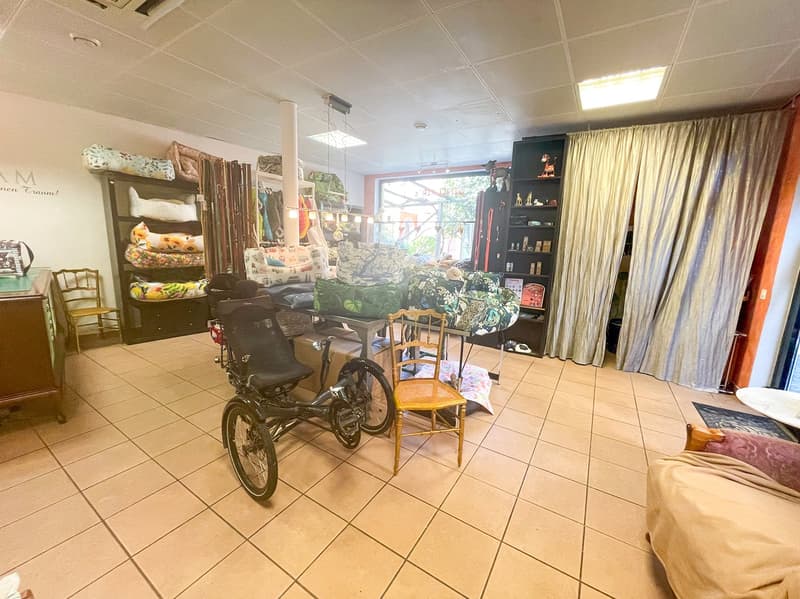tiled floor, trike, shelves with items, armchairs, cabinet, window, curtains