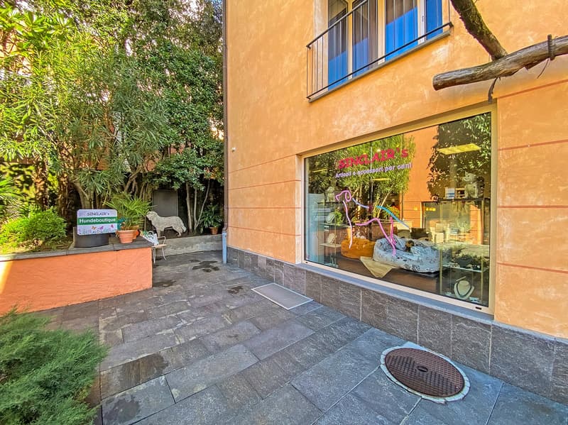 Facade with outdoor display for dog accessories and boutique, paved floor, balcony with railings, and several plants and a sheep statue