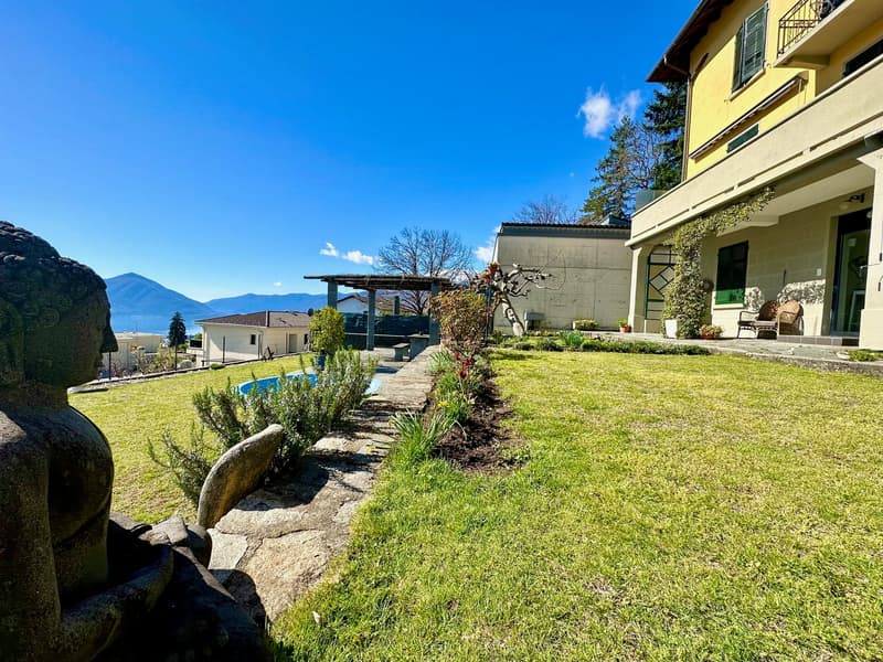 lawn, greenery, small pool, statue, distant mountains, houses, balcony