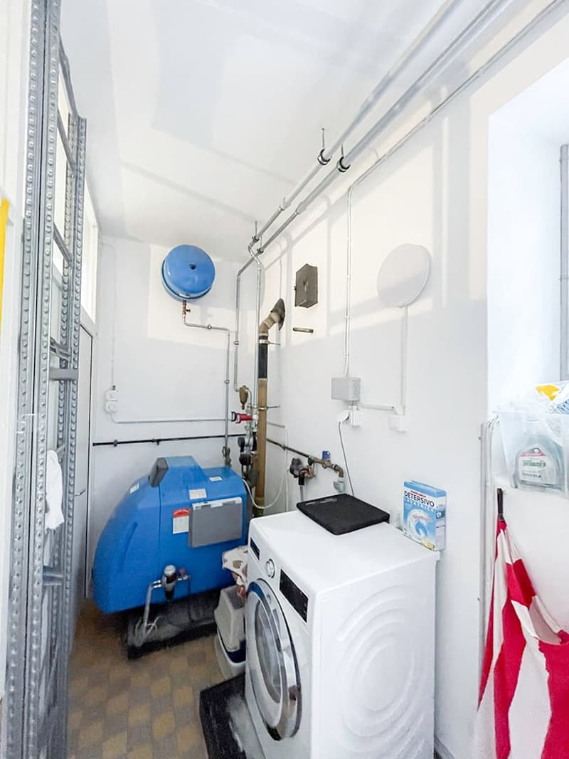 room with laundry facilities and pipes, washing machine and dryer, blue tank on the wall