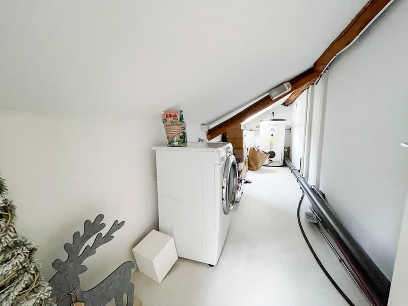 Small space with white appliances, white ceiling, water heater on wall, decorative object, white tiles, wooden beams