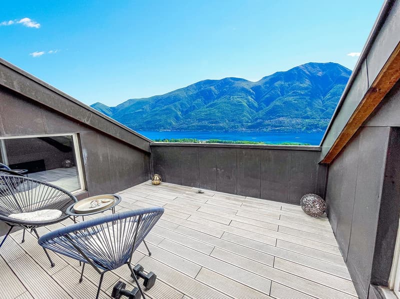 Wooden floor, metal chairs, table, two dumbbells, black railings, mountain view, blue sky