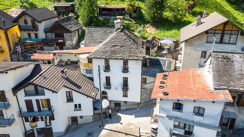 group of houses with multiple balconies and windows, small yard, hilly environment