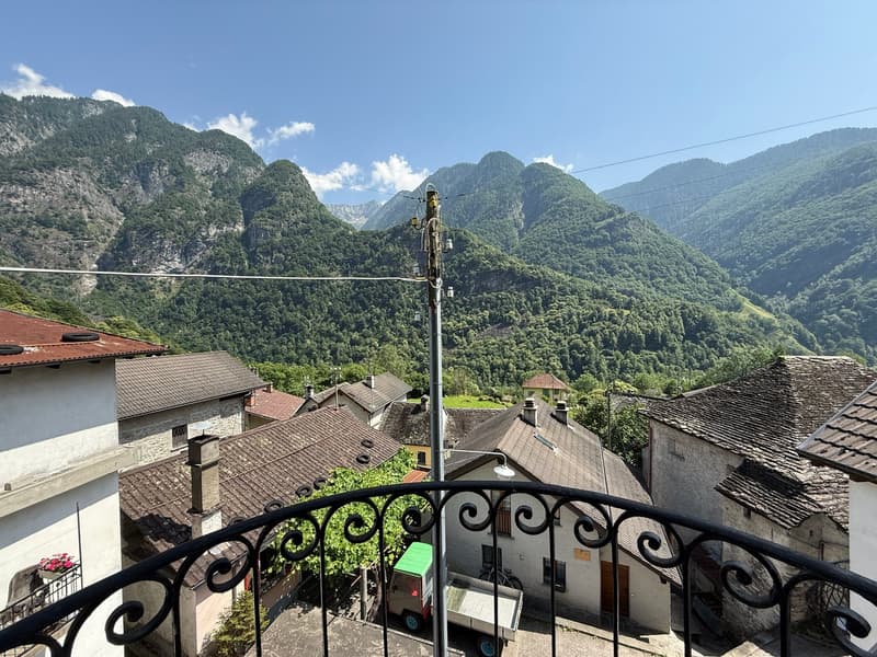 balcony, houses with tiled roofs, valley with mountains, green valley in between