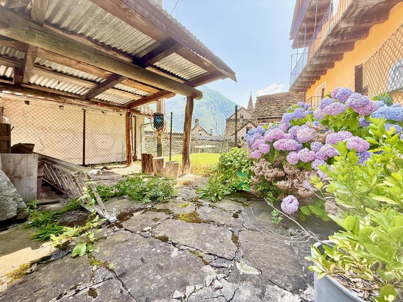 garage entrance with wooden structure, stone pathway, fence, overgrown plants